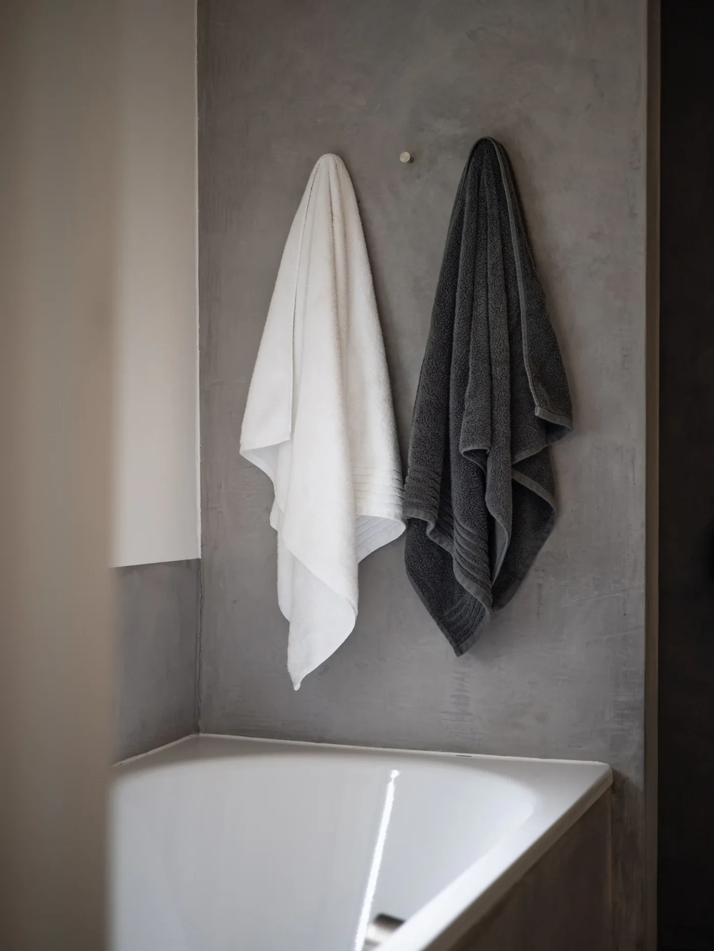 White and charcoal towels hanging against a gray wall