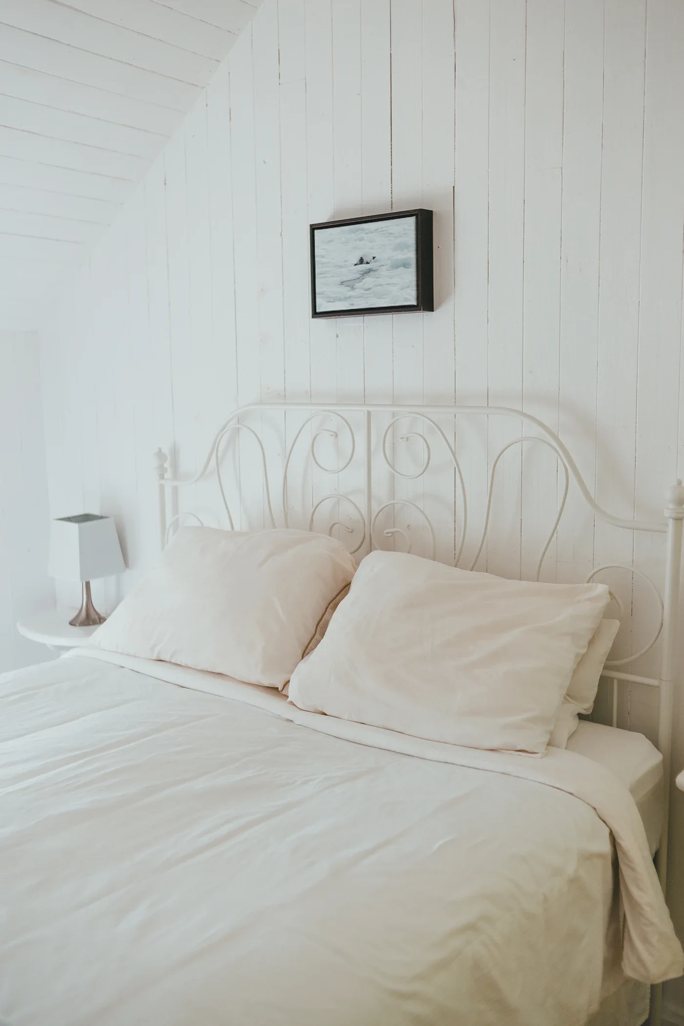 White metal bed frame with layered white bedding