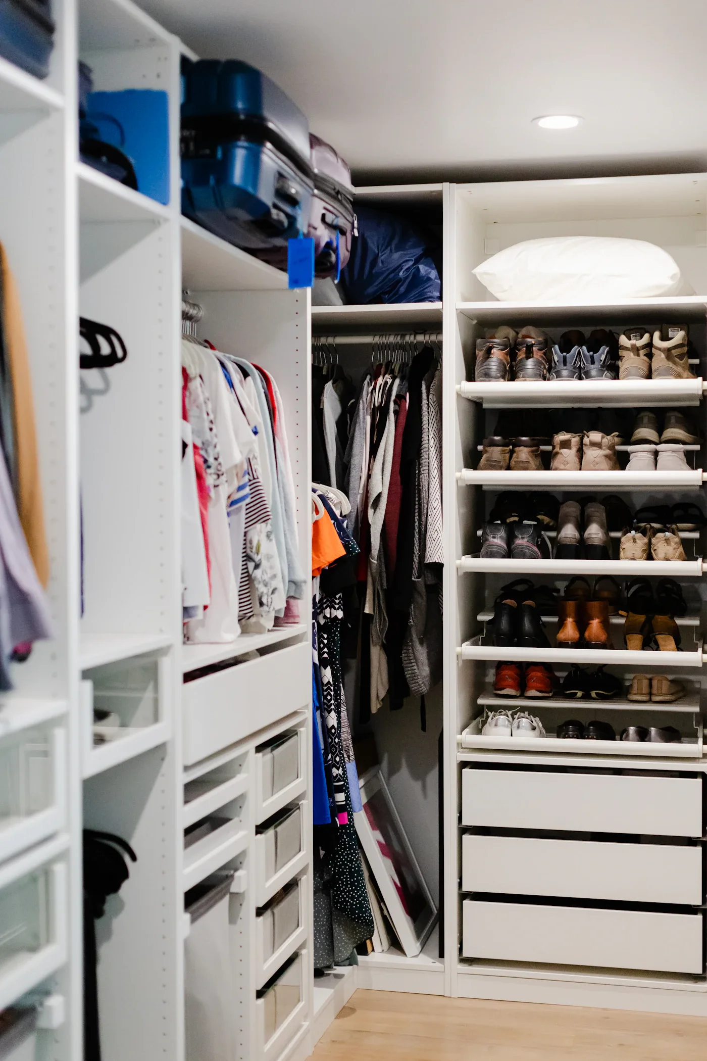 Closet with hanging clothes, shelves, and rows of organized shoes