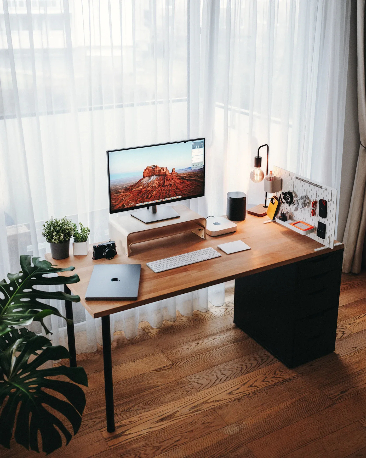 Wooden home office desk with a monitor and a pegboard organizer