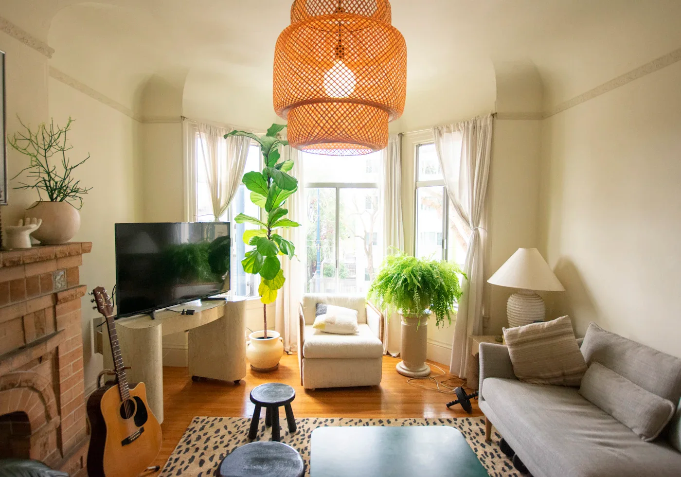 Living room with a woven pendant light, plants, and a cream sofa