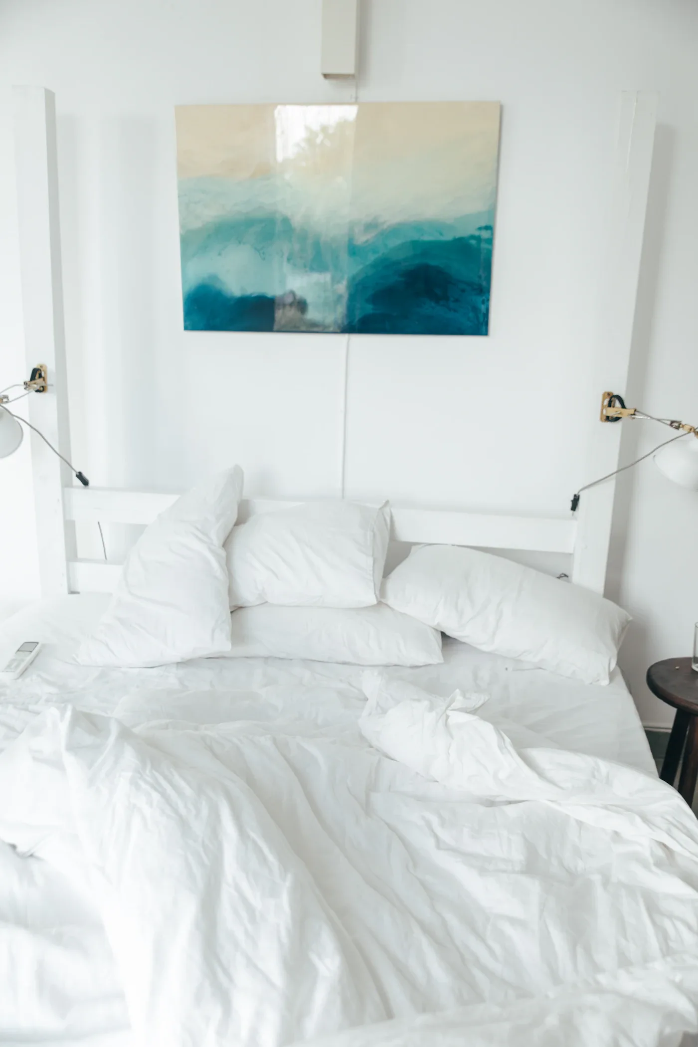 Soft white bedding in a bright bedroom with blue artwork