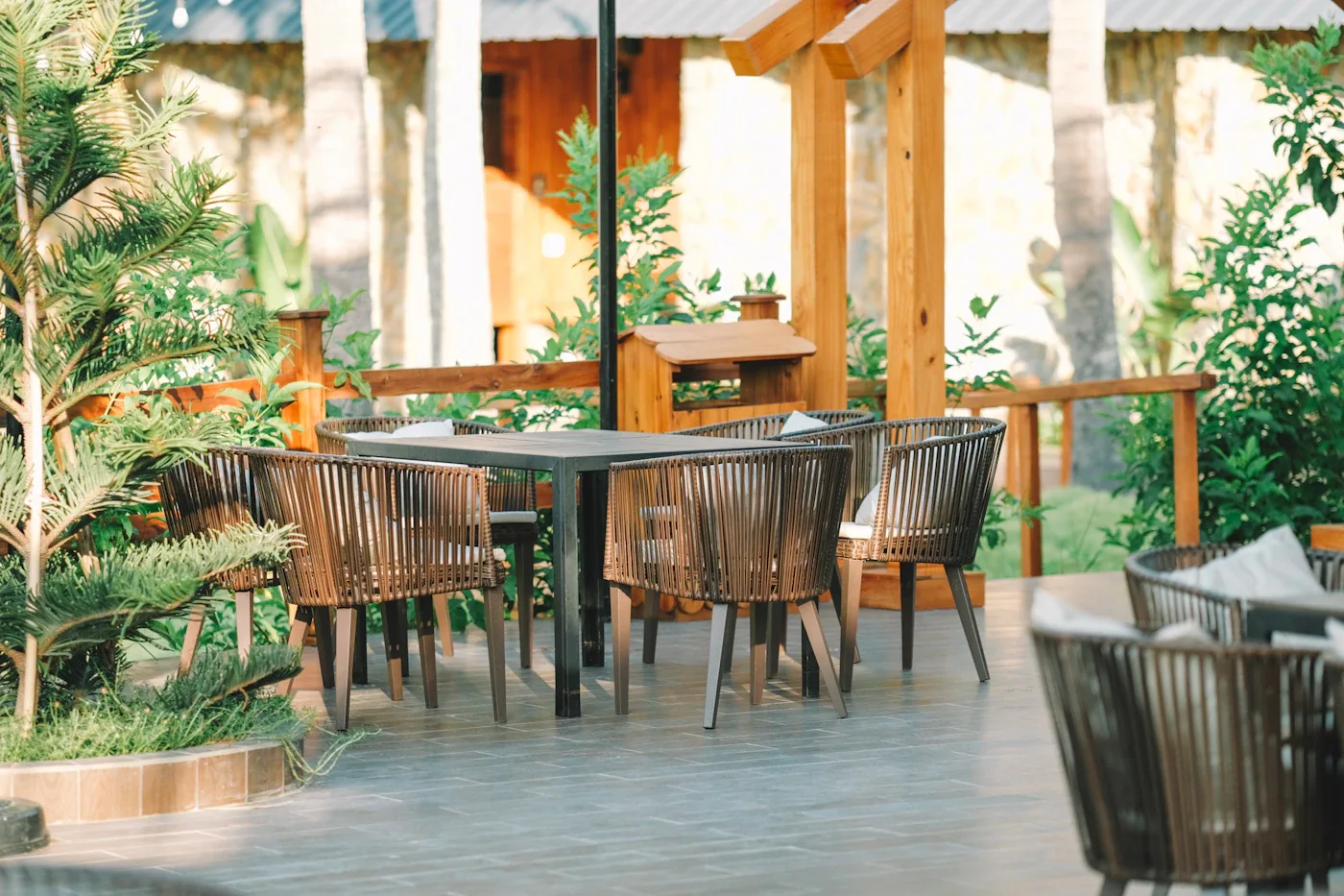 Outdoor dining table and woven chairs beside a covered terrace