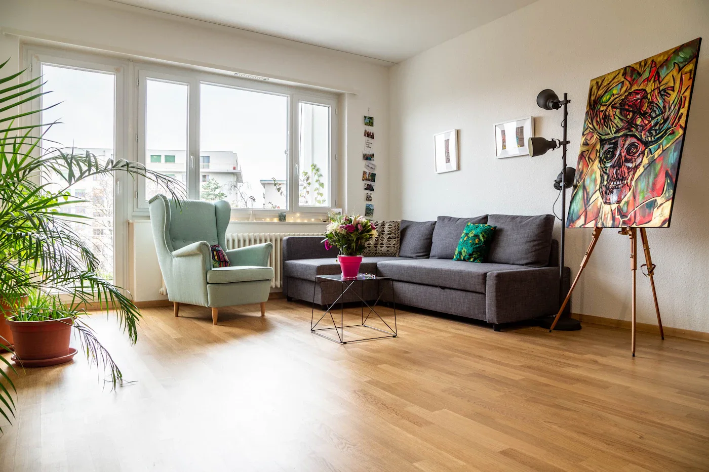 Gray sectional sofa and green armchair beside bright windows