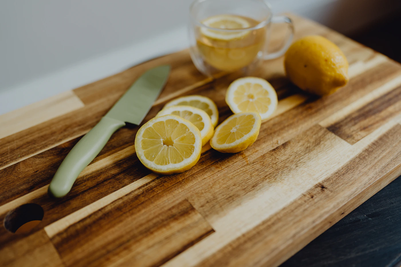 Sliced lemons and a knife on a wooden cutting board